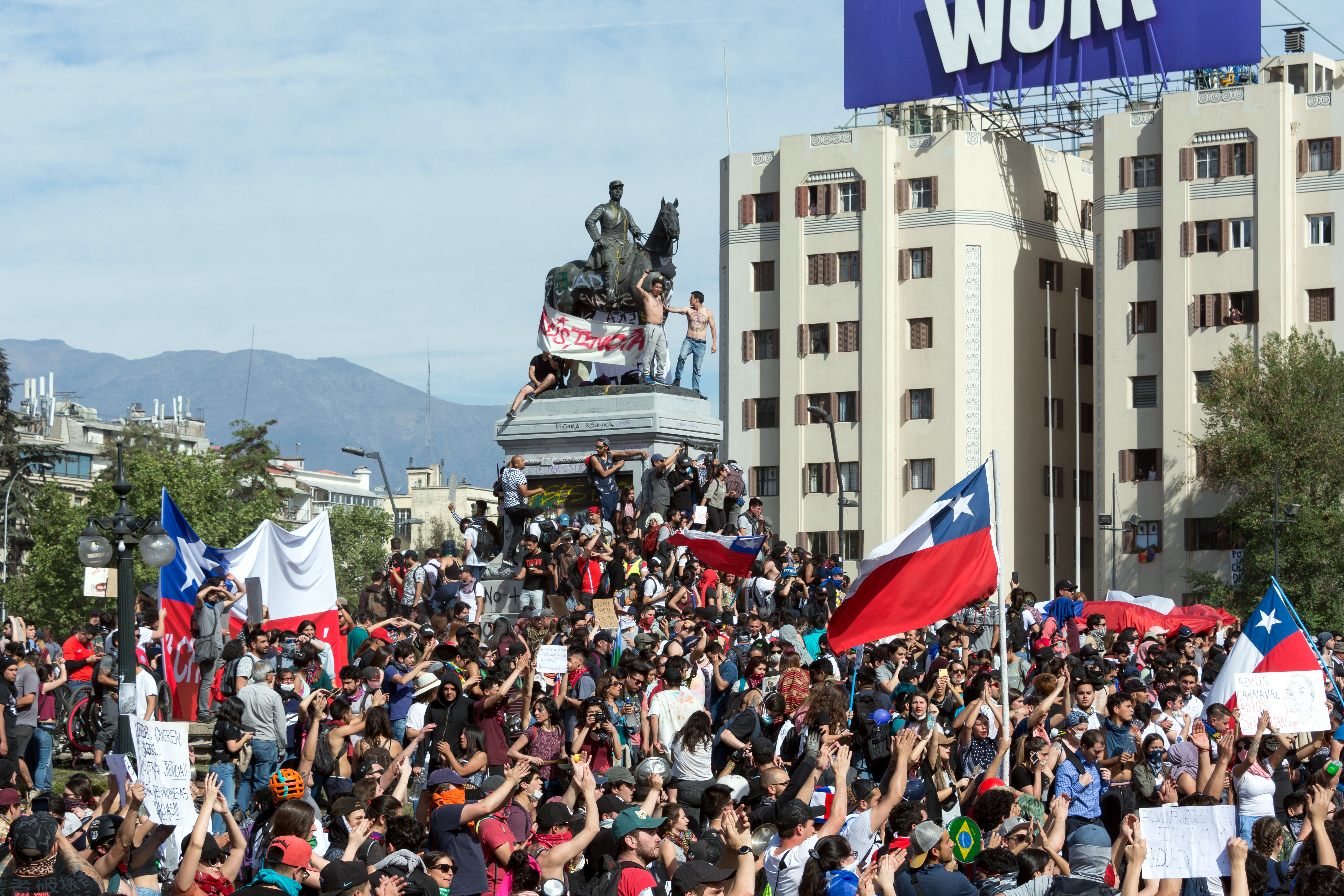 Protest uliczny w Santiago de Chile, w tle pomnik konny i wieżowiec